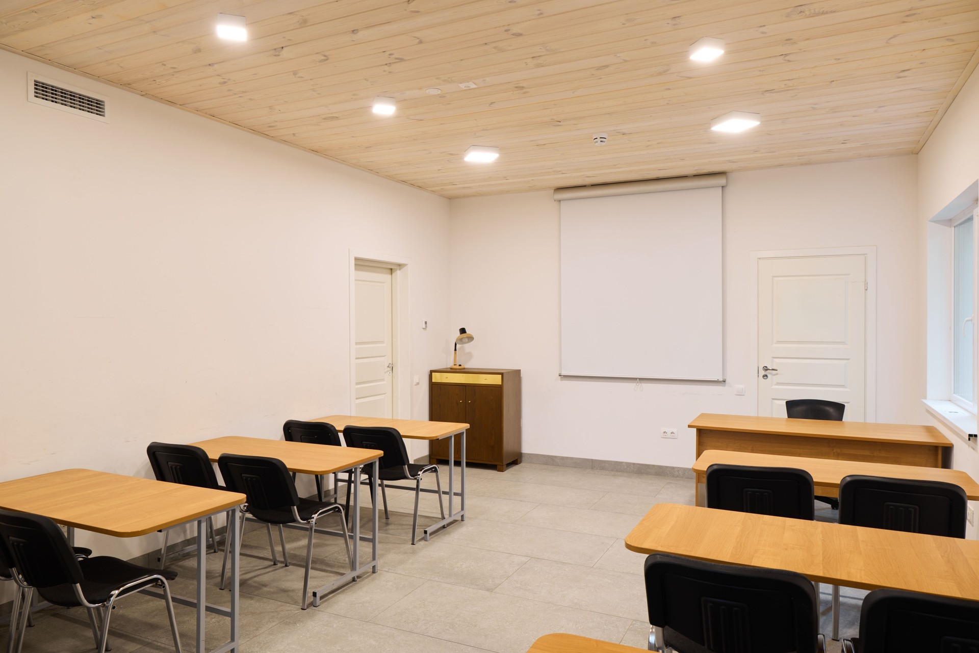 A spacious and modern classroom designed for effective learning, featuring desks and a projector
